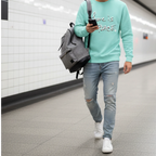 Man wearing a mint crewneck with Love is Peace lettering, headphones and jeans while walking through a tiled subway passage.