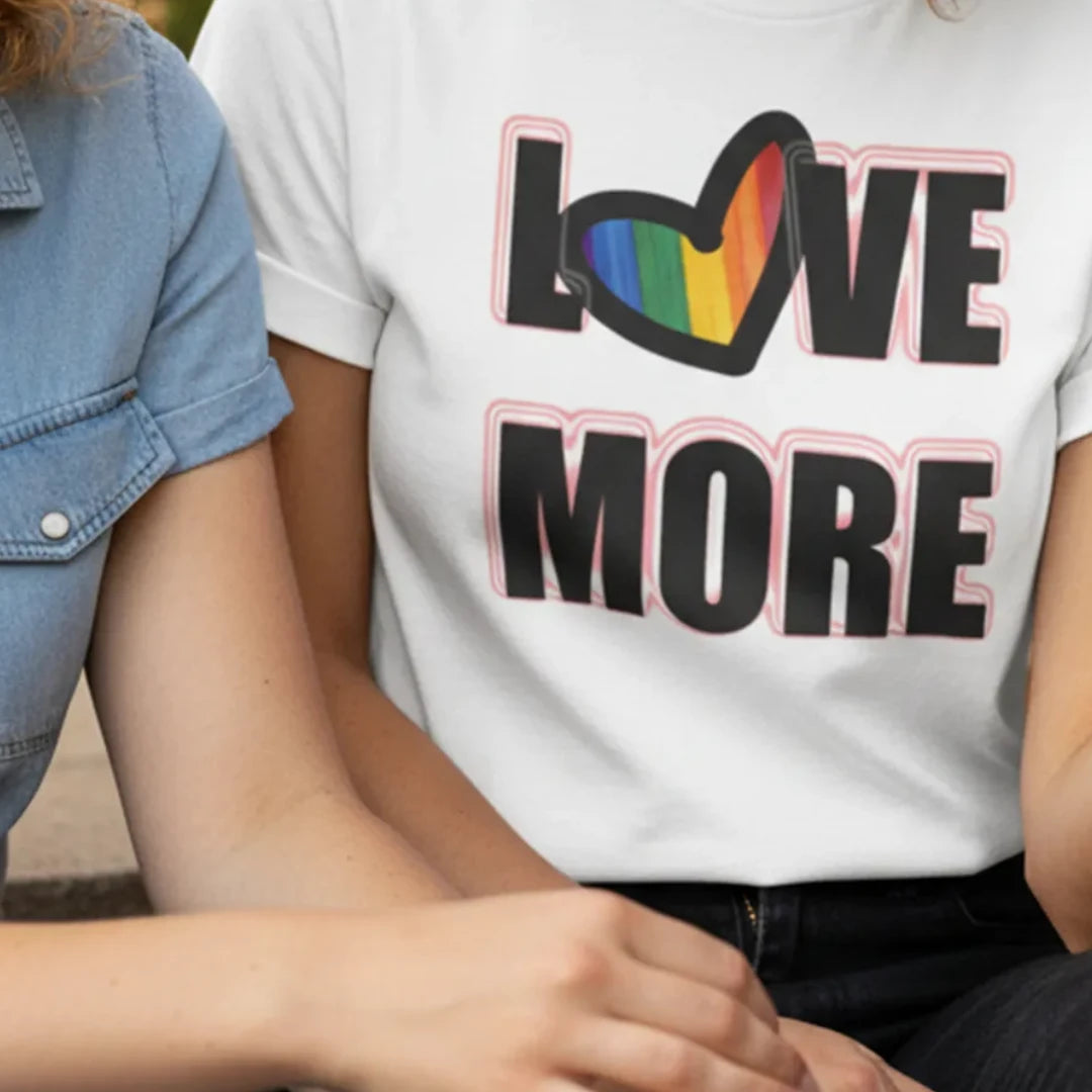 Person wearing a white t-shirt with 'LOVE MORE' text and rainbow heart design.