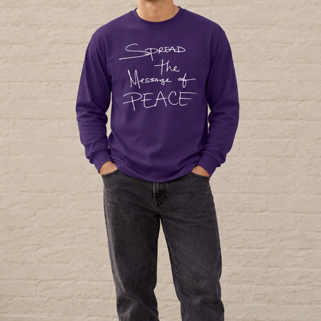 Model wearing a purple Message of Peace long-sleeve tee with washed-black jeans outdoors.
