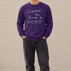 Model wearing a purple Message of Peace long-sleeve tee with washed-black jeans outdoors.