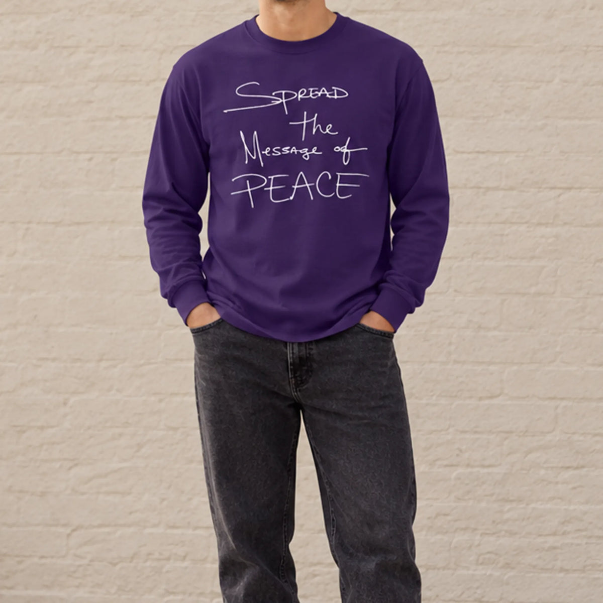 Model wearing a purple Message of Peace long-sleeve tee with washed-black jeans outdoors.