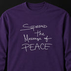 Close-up of a purple long-sleeve tee with white handwritten lettering reading Spread the Message of Peace.
