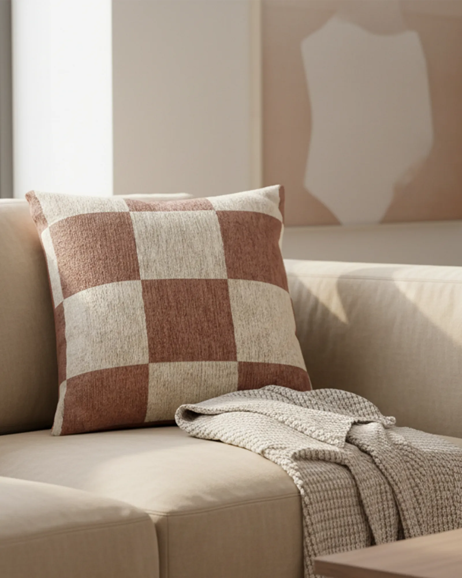 A preview of the Mimosa Pink Woven Checker Pillow, showing a mimosa pink checker pattern on an oatmeal cream colored background with golden hour lighting in an earthy styled modern living room. 
