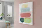 The Freebrd "Geo Req” 30x40 Modern Pastel Minimalist Wall Art on a 1.25 inch thick canvas hanging on a wall in a modern minimalist bathroom, showing an abstract folded towel artwork with fresh green, danish blue, adore pink, abstract teal and butter yellow designs.