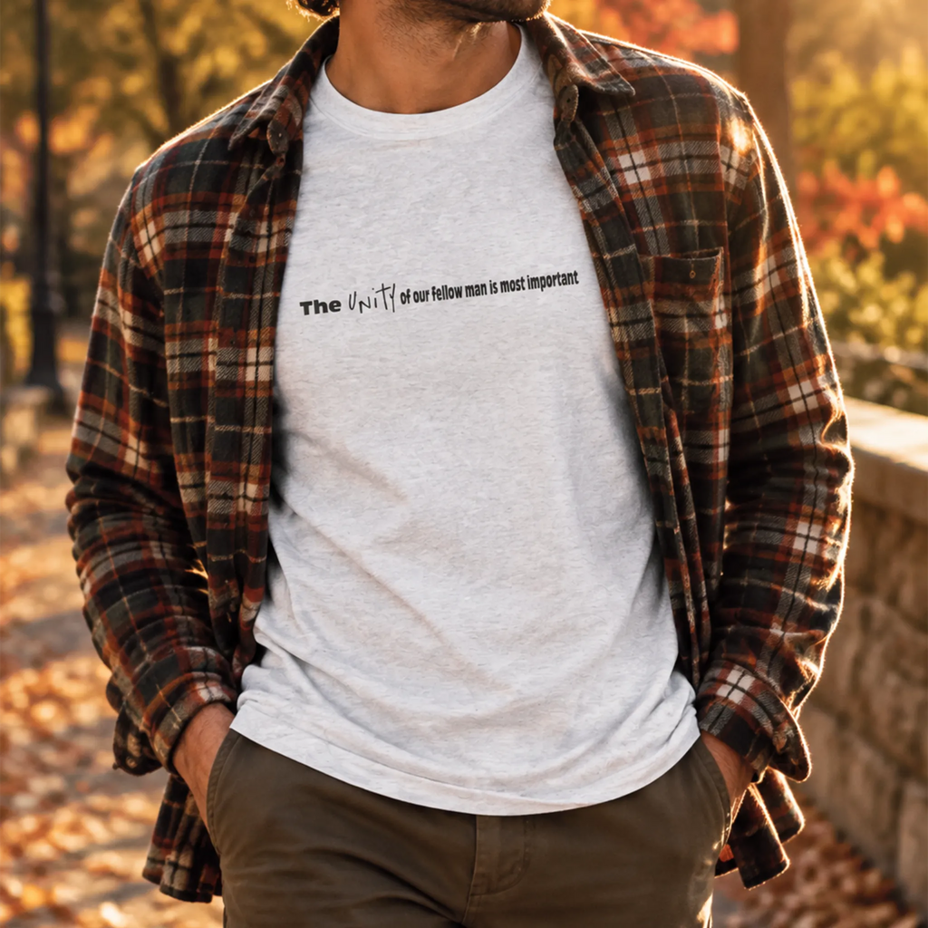 Heather White crew tee worn layered under an open plaid flannel with dark khaki pants, outdoor fall setting, chest text visible.