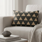 Modern black beige geometric triangle lumbar pillow styled on a couch in a modern living room.