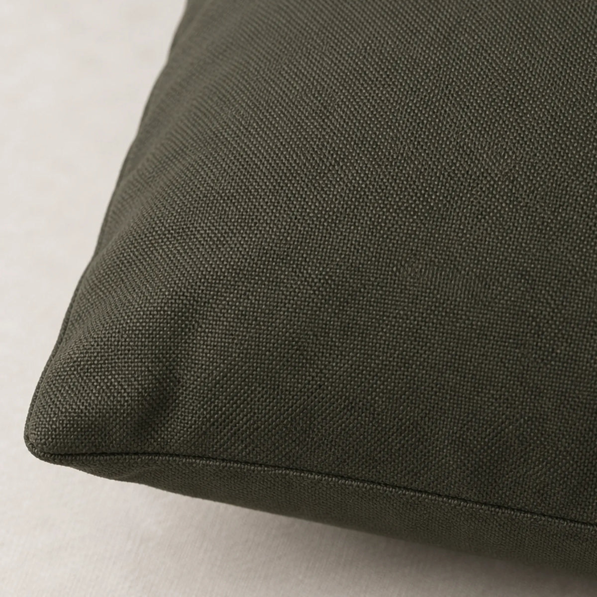 Close-up of the Moss Bronze pillow cover showing its dark gray-olive woven surface and stitched edge.