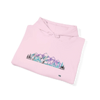 Folded light pink pullover hoodie showing a purple, turquoise and gray mountain and evergreen tree graphic, with the hood and drawstrings visible.