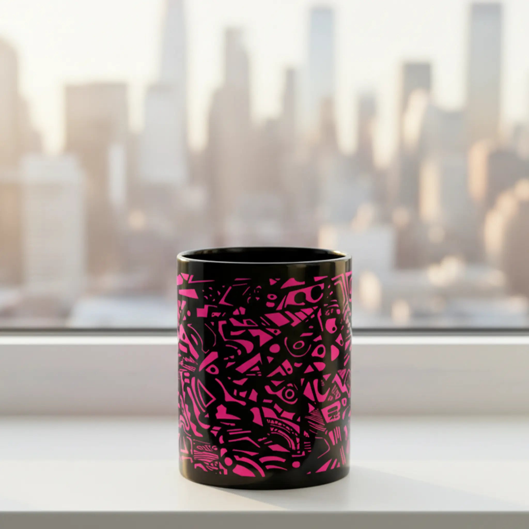Freebrd Medicolo neon pink abstract black ceramic mug sitting on a windowsill with soft golden sunrise light and blurred urban city skyline in the background.