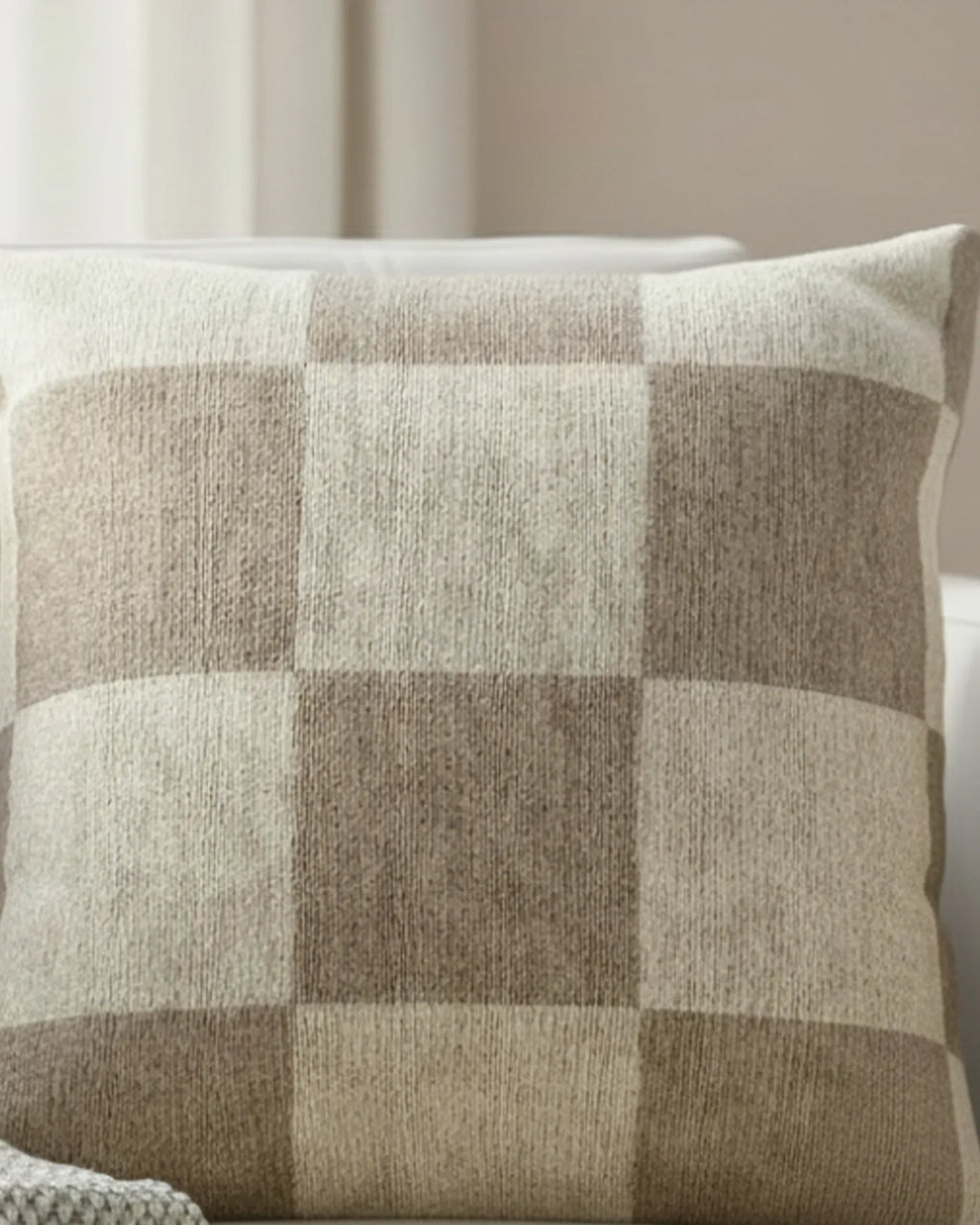 White linen armchair in a soft minimalist living room with sheer curtains and natural window light styled with the Neutral Beige Checkered Woven Pillow.