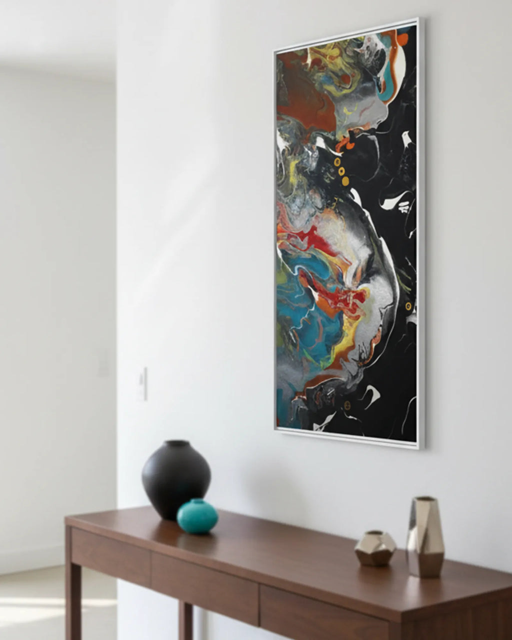The white framed  ‘Silver Bird’ FREEBRD abstract painting on a white wall above a brown wooden console table with decorative decor items.