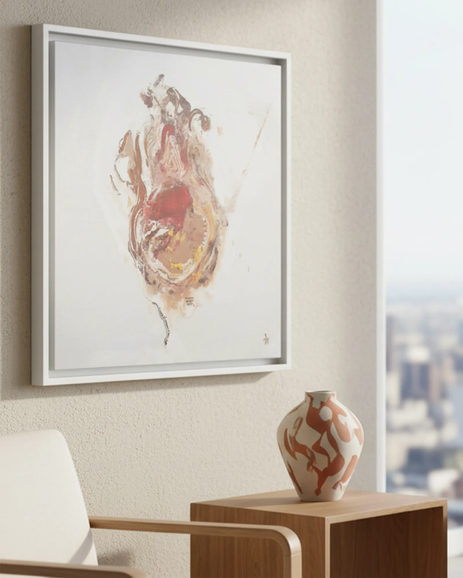 White framed abstract art on a wall with a white and terracotta vase on a wooden table below.