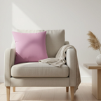 Beige armchair with a Pastel Dust Violet faux suede throw pillow and a blanket in a minimalistic nordic styled room.