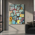 Freebrd "Patchy" unframed urban abstract canvas art, 30x40 vertical, hung in a modern urban loft with concrete wall, dark charcoal sofa, and black accent pillows — sky blue, mustard yellow, hot pink graffiti, and white drip details in window lighting.