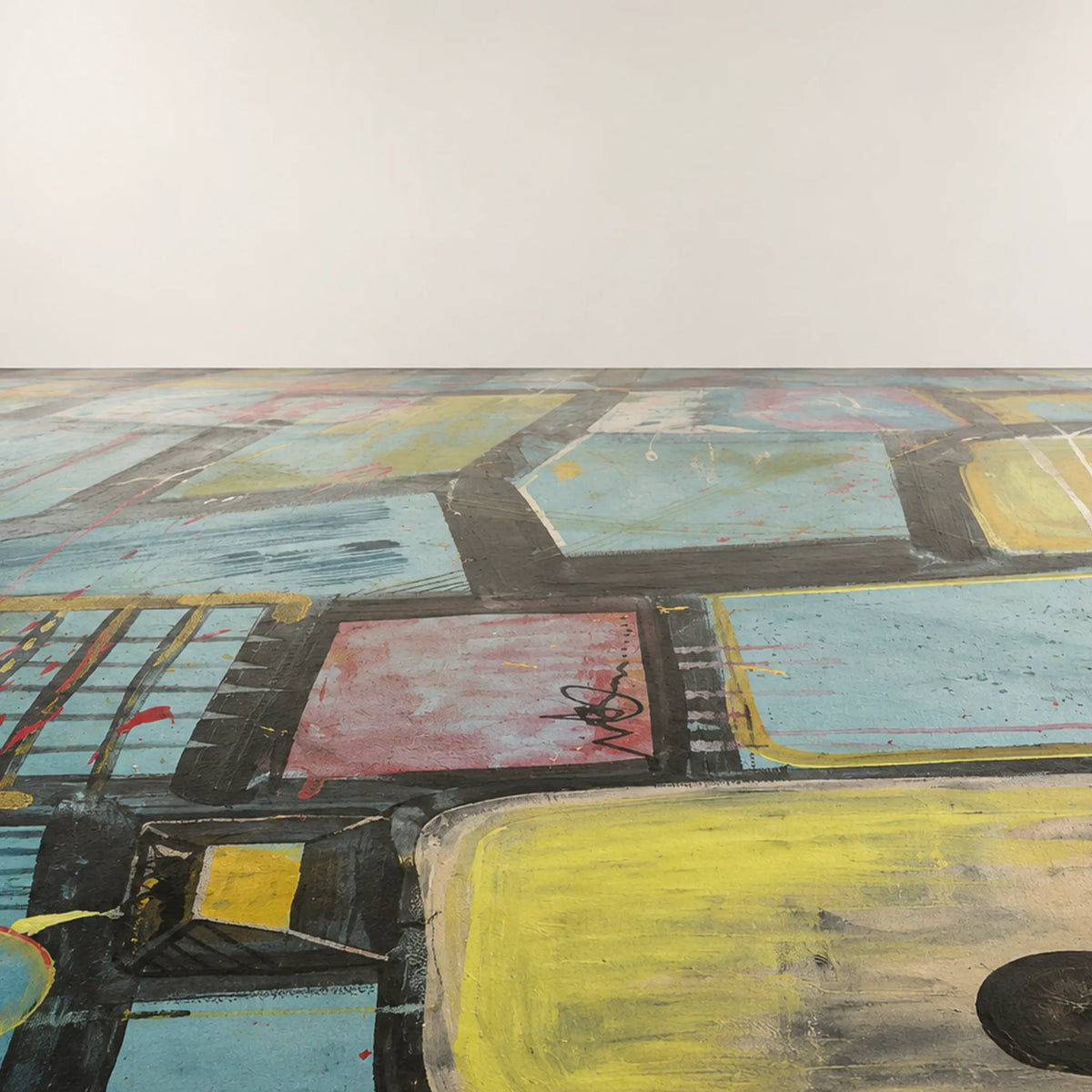 Painted floor with blue-green, yellow, and muted pink geometric panels, black outlines, circular marks, and white streaks receding toward an off-white wall.