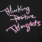 Classic fit crew neck tee, black, close-up texture showing cotton fabric weave and handwritten script graphic reading Thinking Positive Thoughts in white with hot pink outline.