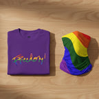 Purple t-shirt bundle with 'Freedom!' in rainbow colors and a rainbow flag on a wooden surface.