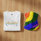 White t-shirt bundle with 'Freedom!' in rainbow colors and a rainbow flag on a wooden surface.