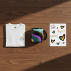 White peace pride t-shirt with rainbow peace symbol, a colorful LGBTQIA rainbow mug, and sheet of pride stickers on a wooden surface.