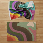 Colorful rainbow flag and a colorful rainbow coir door mat with wavy pattern on a wooden surface.