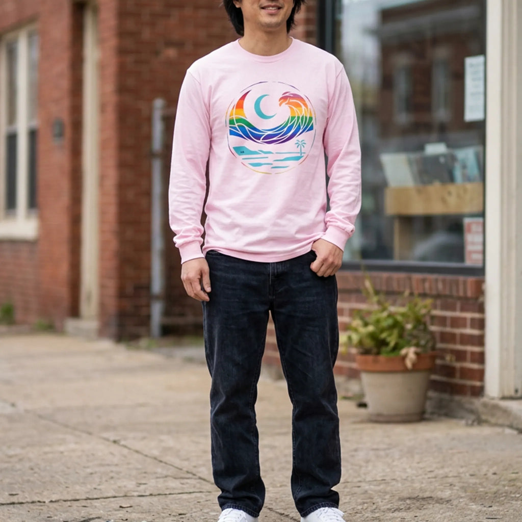 Person wearing a light pink long sleeve tee with a rainbow wave and turquoise crescent moon graphic outside a record shop.