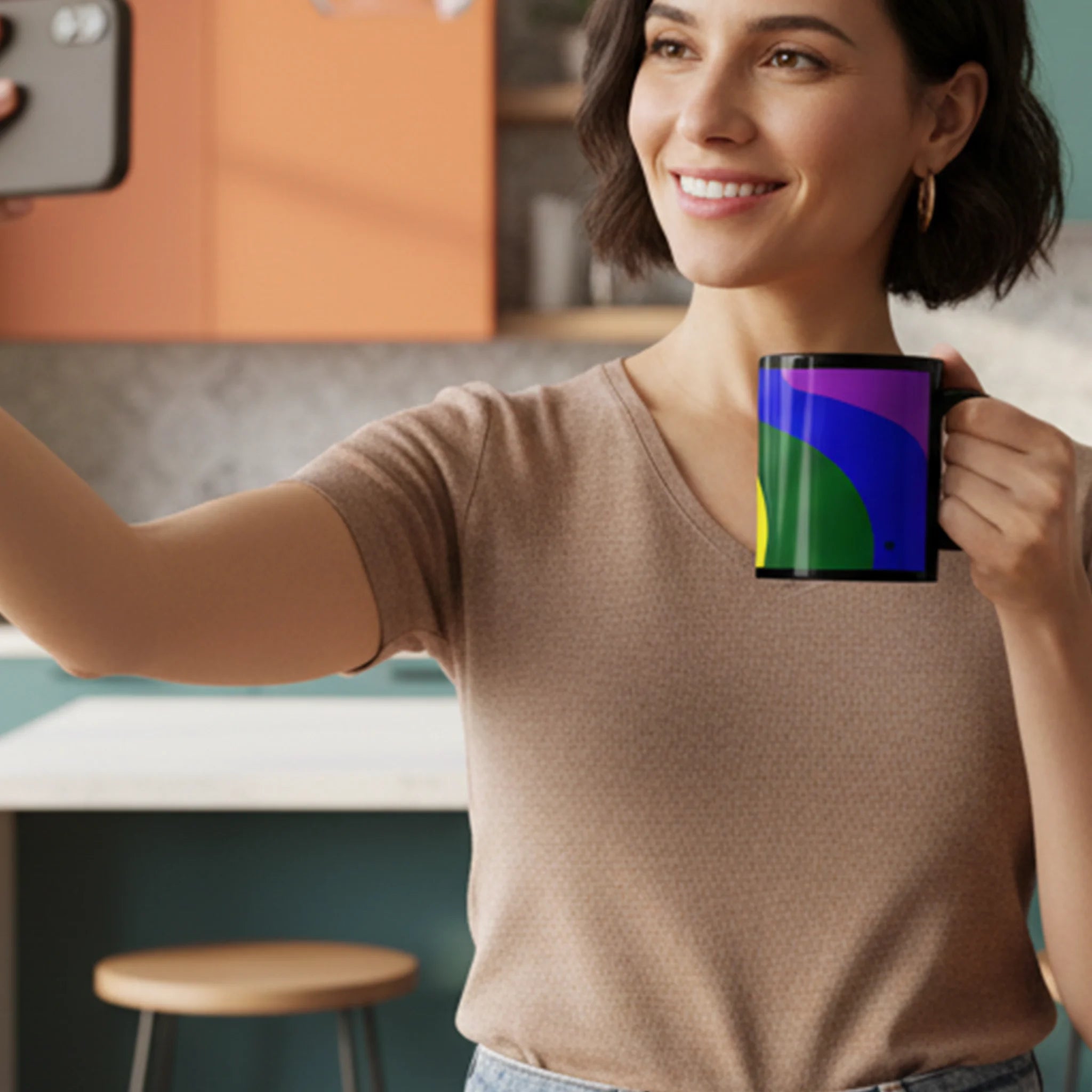 Woman in kitchen taking selfie holding black FREEBRD rainbow wave ceramic mug with purple blue and green pride design.