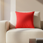 A rich red faux suede throw pillow on a cream accent chair, lifestyle view.