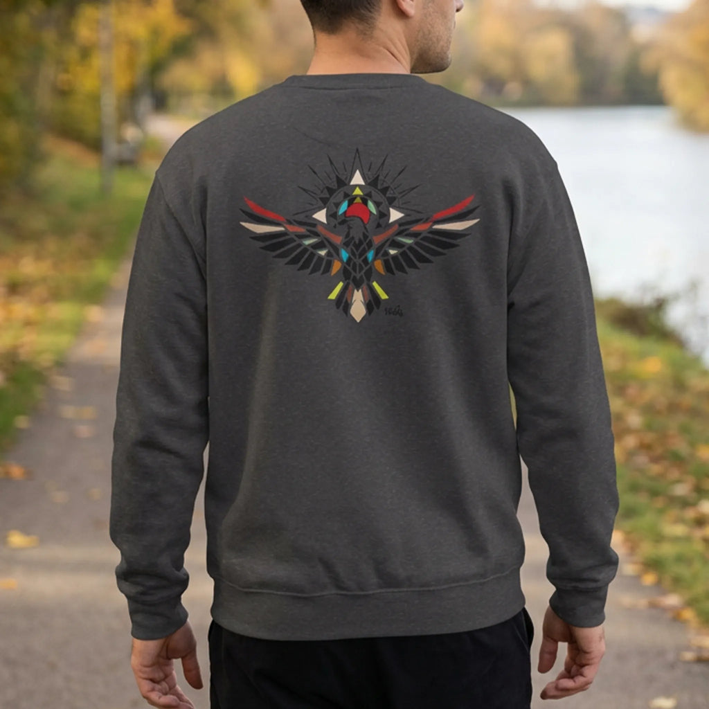 Person on an autumn riverside path wearing a dark grey heather sweatshirt with a colorful geometric bird graphic on the back, rear view.