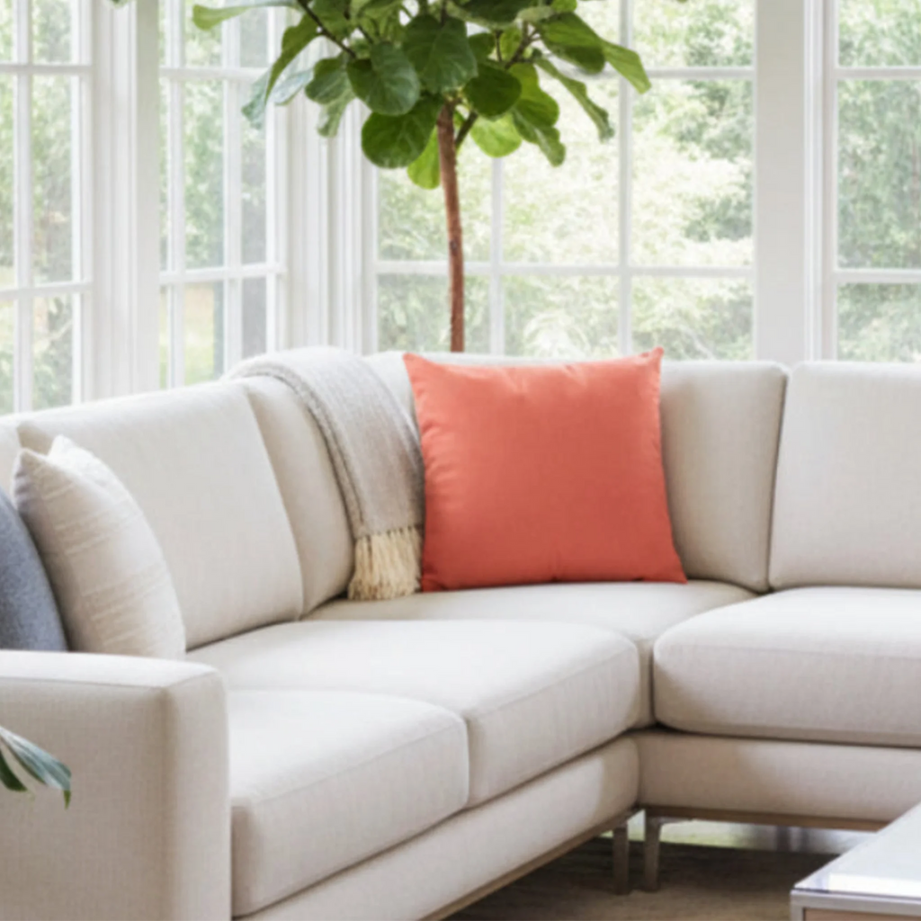 Salmon red faux suede pillowcase styled on a couch in a modern sunroom.