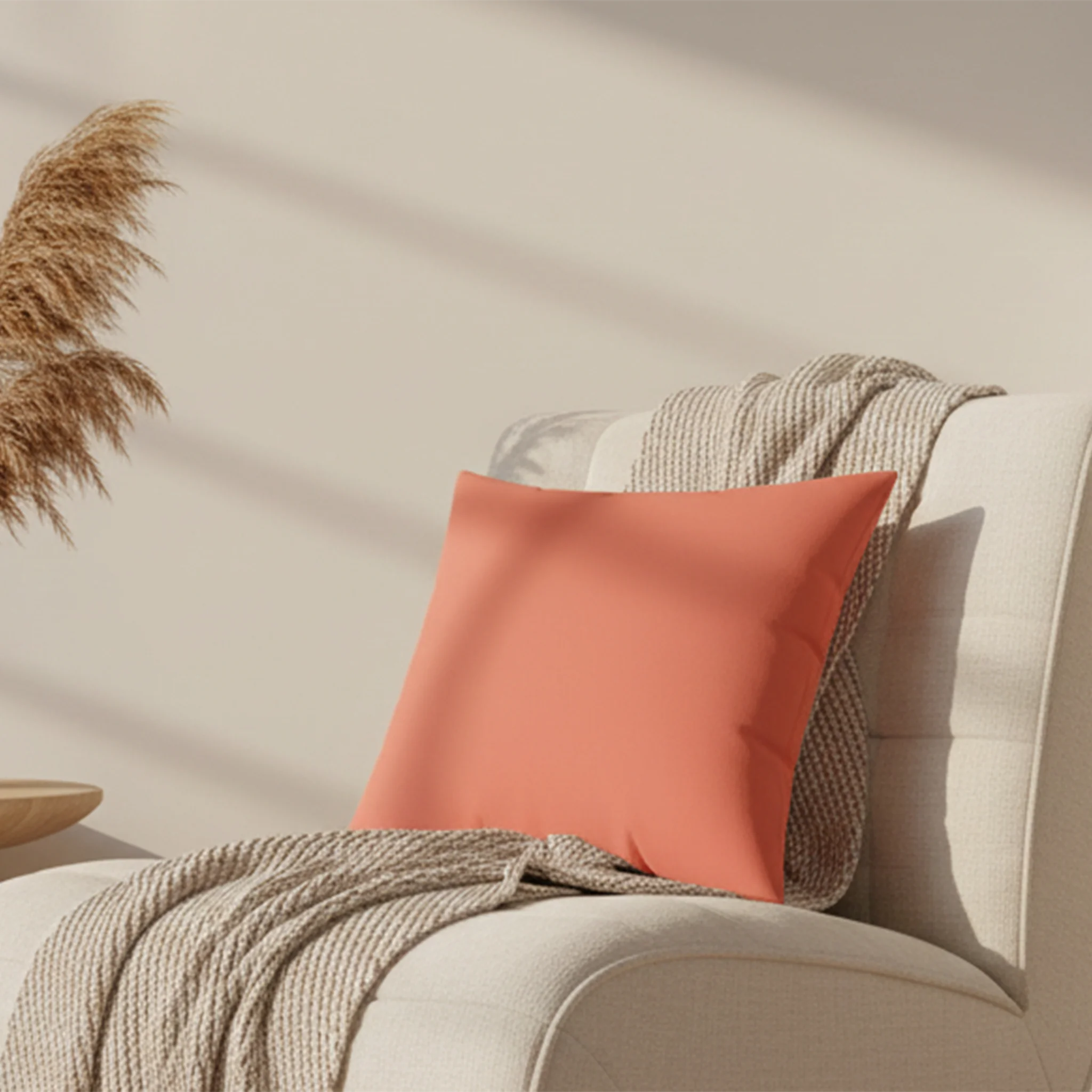 Salmon red faux suede pillow styled on a sofa chair, warm coral pink home decor.