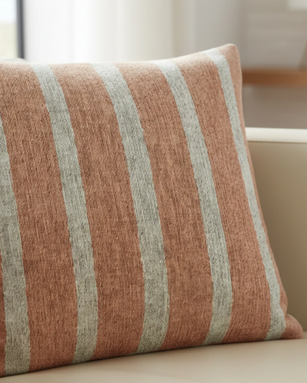 Cream fabric sofa in a bright airy living room with warm wood floors and sheer curtains styled with the Salmon Red Stripe Woven Pillow.