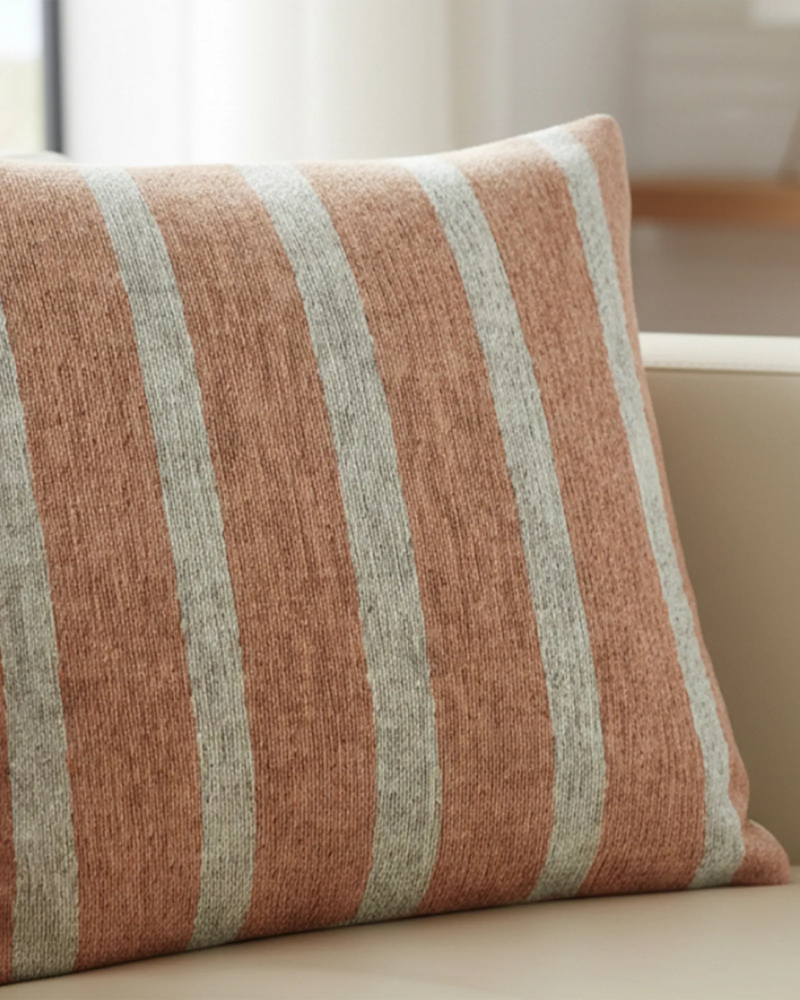 Cream fabric sofa in a bright airy living room with warm wood floors and sheer curtains styled with the Salmon Red Stripe Woven Pillow.
