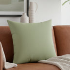 Schist green faux suede throw pillow styled on a chestnut leather couch  in a modern living room, lifestyle view.