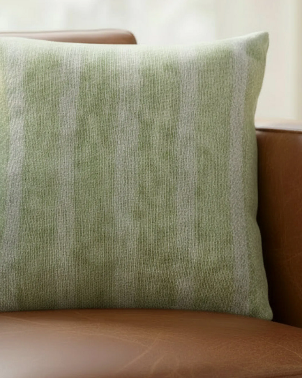Cognac brown leather sofa in a warm natural light living room styled with the Schist Green Stripe Woven Pillow.