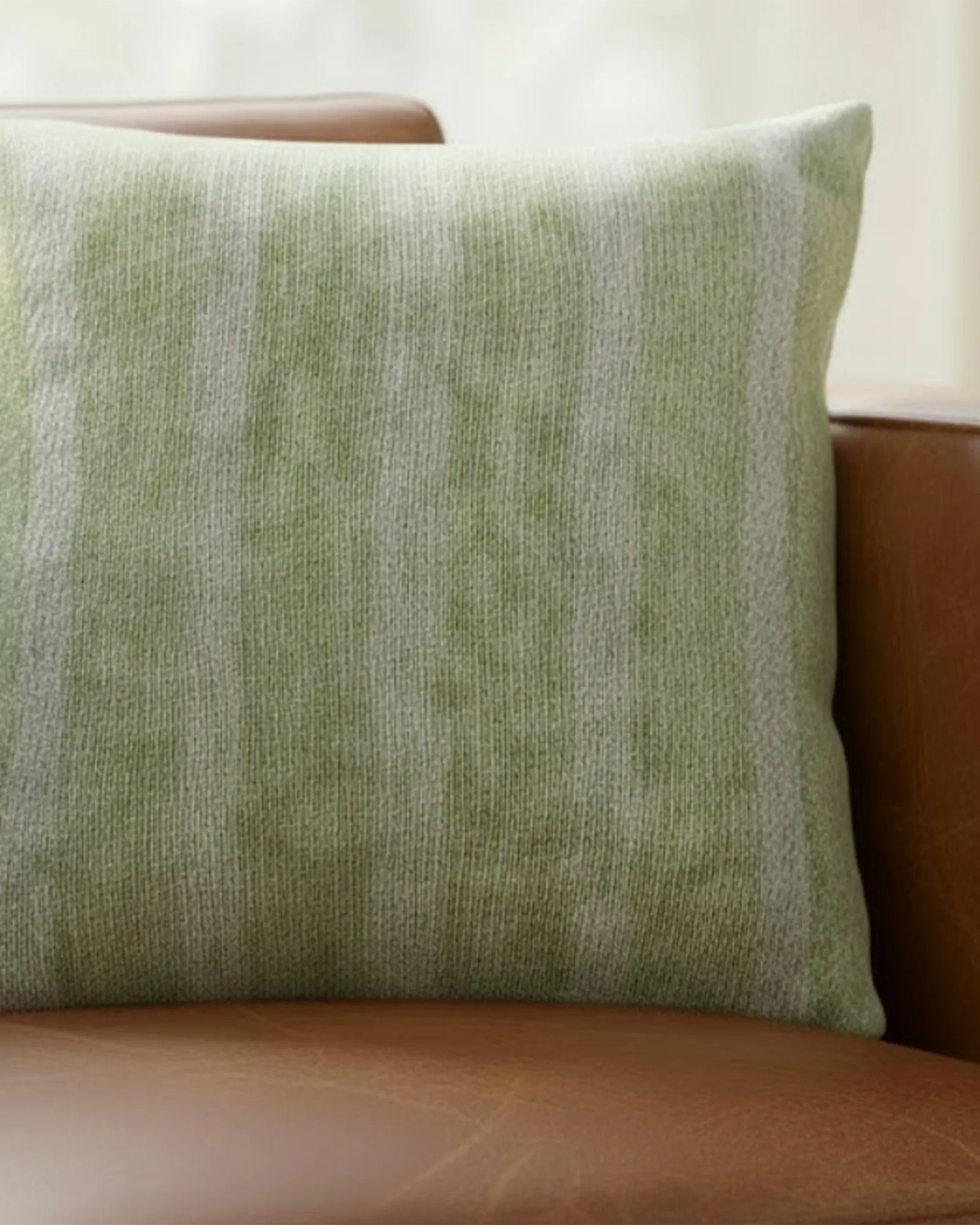 Cognac brown leather sofa in a warm natural light living room styled with the Schist Green Stripe Woven Pillow.