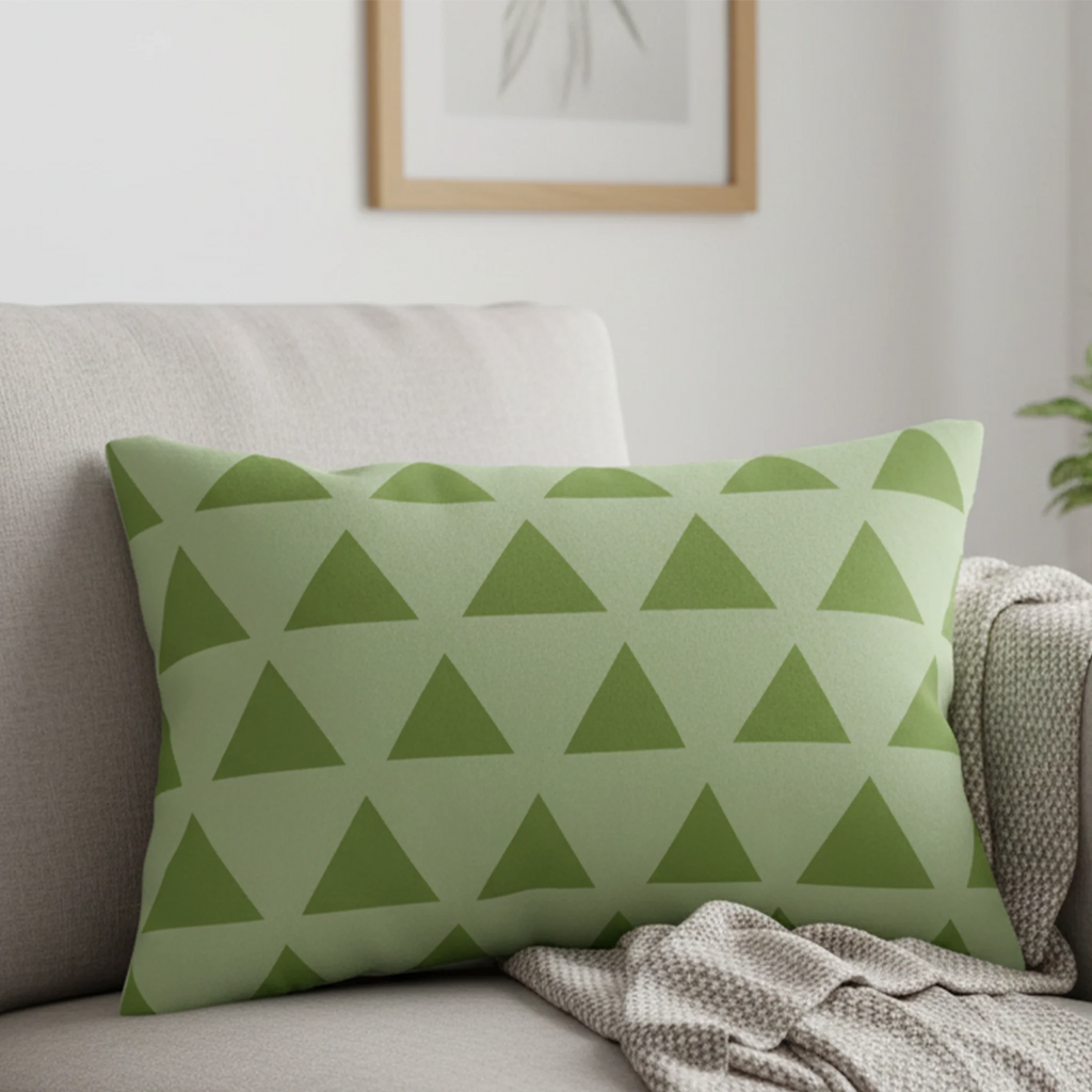 Schist olive green geometric triangle lumbar pillow styled on a couch in a modern living room. 