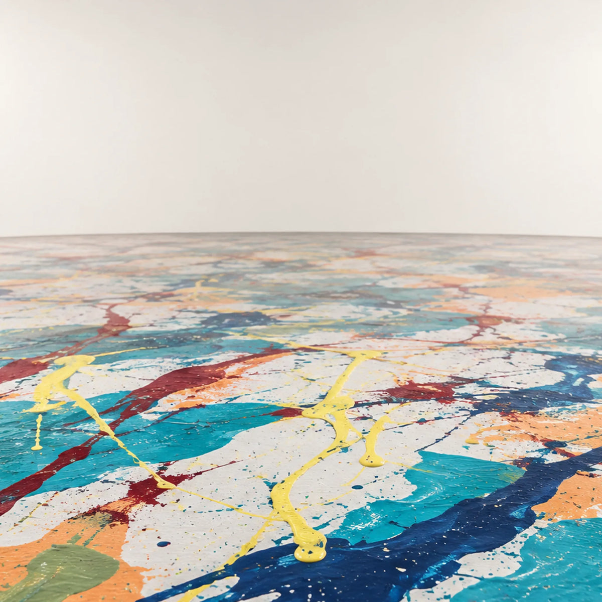 Seaside Mantra-inspired painted floor with turquoise, navy, peach, burgundy, and yellow marks receding beneath a plain off-white wall.