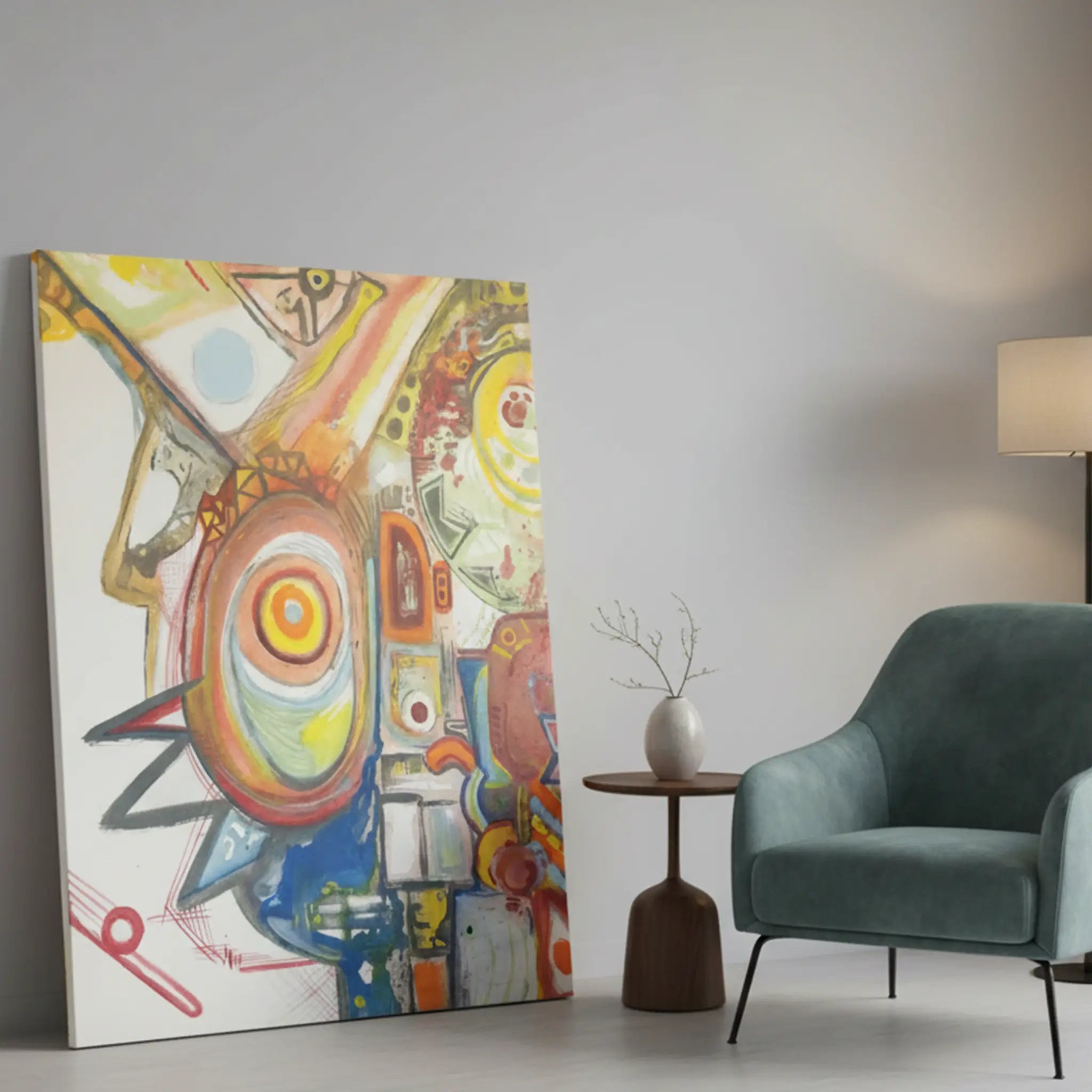 Freebrd "Sky Man" unframed abstract canvas art, 36x48 vertical, 1.25" thick, leaning against modern interior wall beside accent sofa chair — size reference featuring bold yellows, oranges, reds, cobalt blue, and green on white.