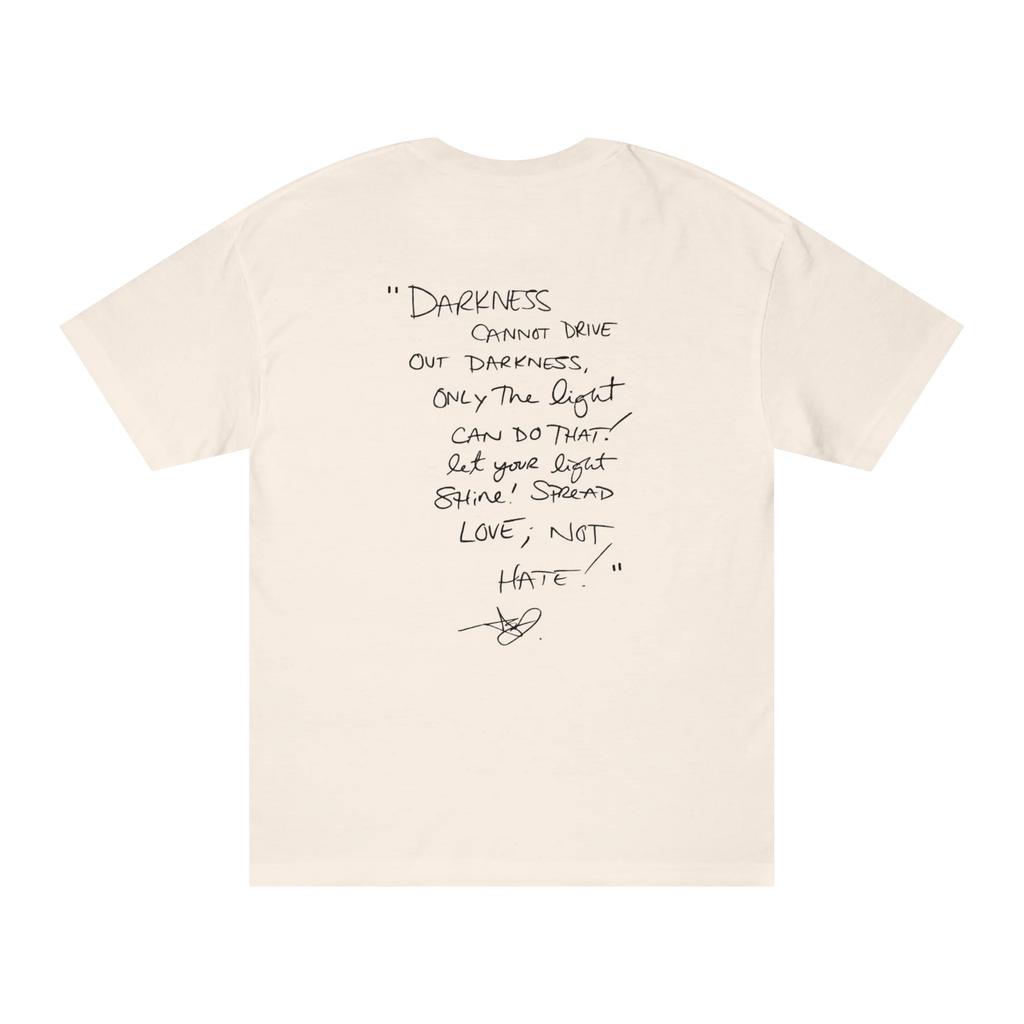 Classic fit crew neck tee, cream, back view, handwritten script quote reading Darkness cannot drive out darkness only the light can do that let your light shine Spread Love Not Hate with signature.