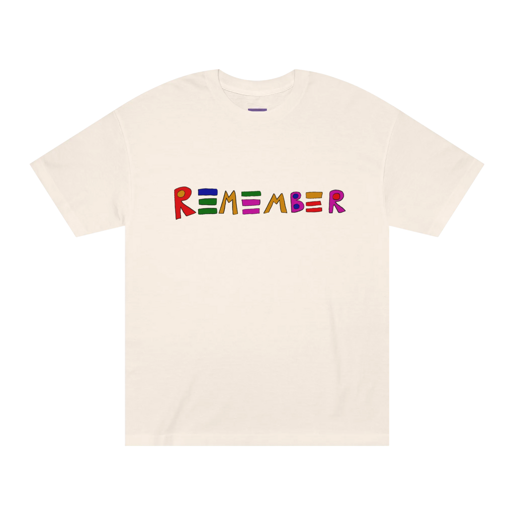Classic fit crew neck tee, cream, front view, hand-drawn multicolor lettering reading REMEMBER in red, blue, green, orange, purple, and pink.