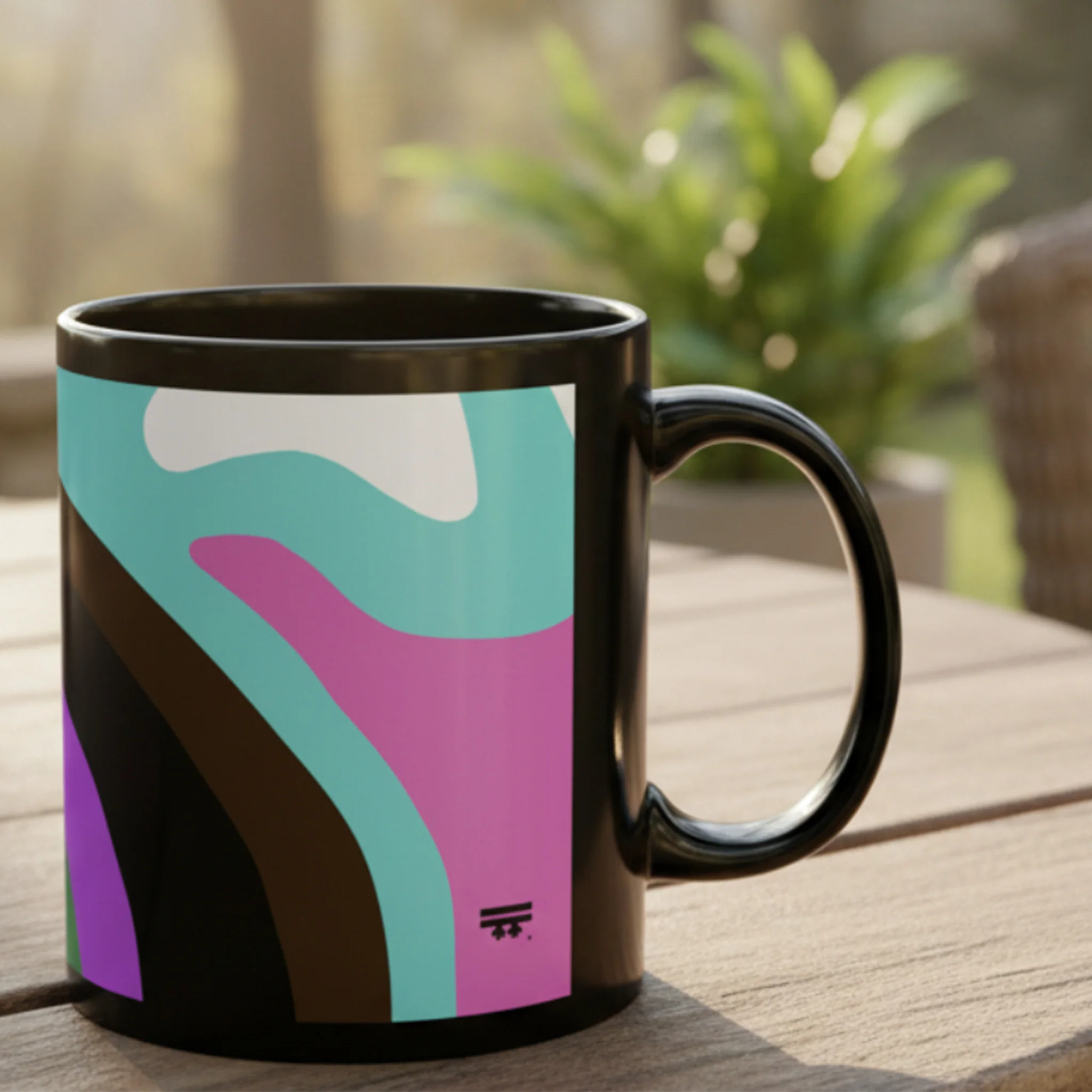 A left side view of the Support Love Ceramic Mug showing the abstract wavy pride pattern in teal, pink, purple, and brown on a glossy black 11oz mug, resting on a wooden outdoor table.