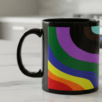 A right side view of the Support Love Ceramic Mug displaying bold rainbow wave stripes in red, orange, yellow, green, blue, and purple on a glossy black 11oz ceramic mug on a white kitchen counter.