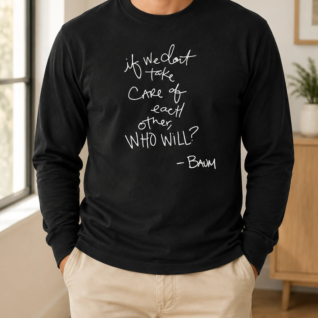 Person wearing a black long-sleeve top with white handwritten quote artwork and light khaki pants, standing in a softly lit room.