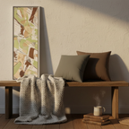 Slim sage abstract canvas leaning against wall with charcoal grey and saddle brown faux suede pillows on wooden bench, cozy reading nook bundle, 12x36 canvas and 18x18 pillows.