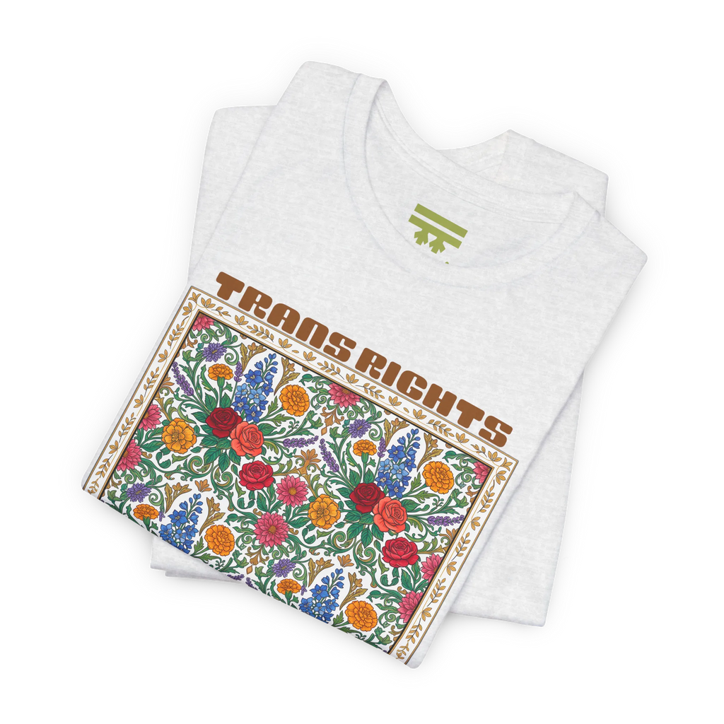 Ash T-shirt shown folded at an angle, with the floral front graphic and Trans Rights Are Human Rights text visible.