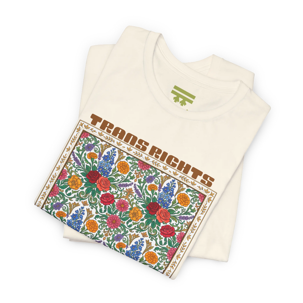 Natural T-shirt shown folded at an angle, with the floral front graphic and Trans Rights Are Human Rights text visible.