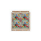 A square magnet with rounded corners featuring a colorful floral pattern in the center and brown text reading 'TRANS RIGHTS ARE HUMAN RIGHTS' at the top and bottom, shown on a plain white background.