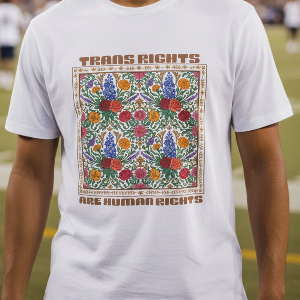 White Trans Rights Are Human Rights floral graphic tee worn by a man at an evening American football game, front view.