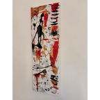 Angled view of a tall, narrow abstract painting on a pale wall, with black figure-like shapes, red and gold patches, and geometric marks on white.