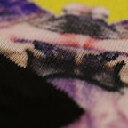 All-over print crew socks with abstract Tribal Wave art, extreme close-up fabric weave detail, deep purple, red, orange, and yellow.